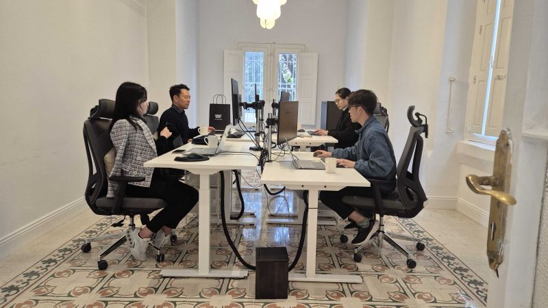 Bright meeting room with a long desk, chairs and monitors