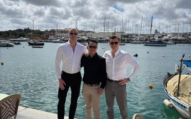 Four SEO Butler team members by a marina with boats and cloudy sky