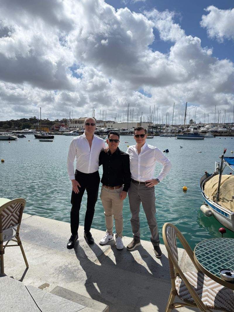 Four SEO Butler team members by a marina with boats and cloudy sky